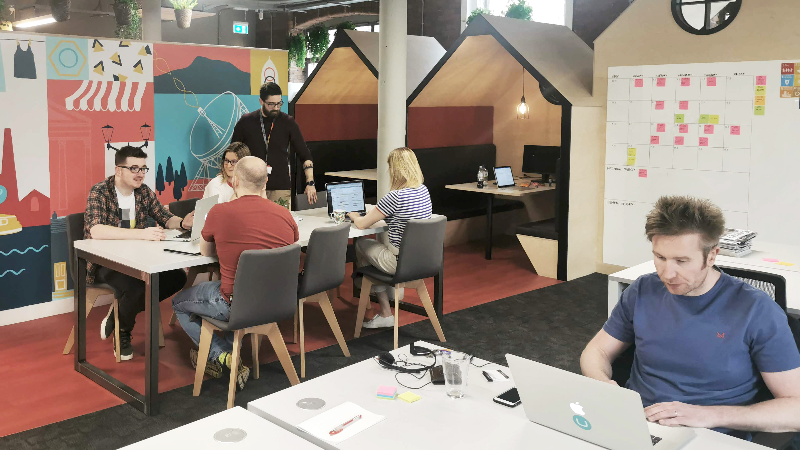 A team sitting around a desk chatting about work in an open office