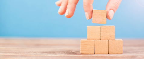 a hand placing a building block onto a stack
