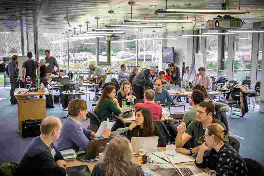 A large room with floor to ceiling windows filled with people working