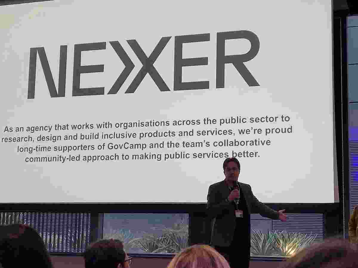 Chris delivers an opening comment to the GovCamp unconference. The Nexer logo can be seen onscreen 
