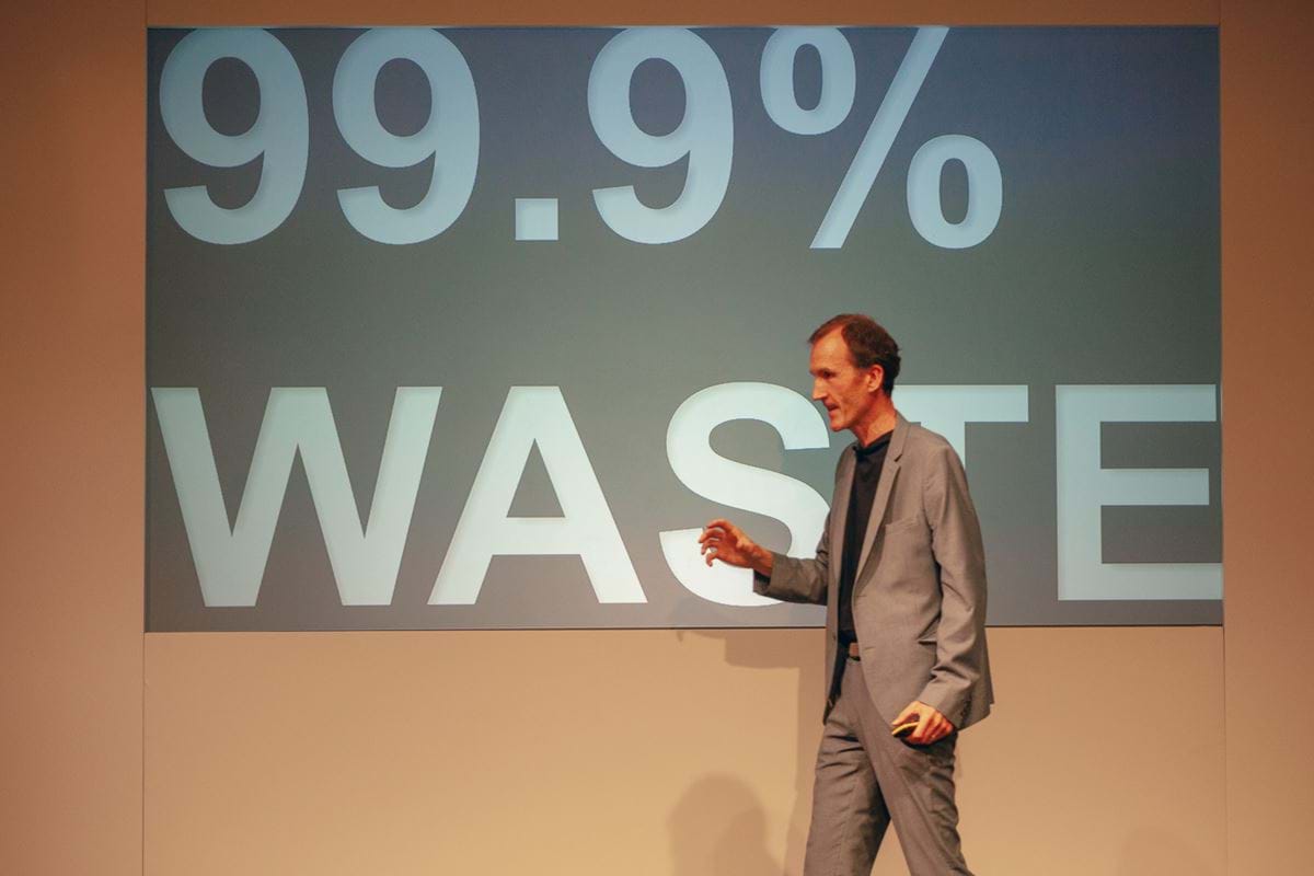 Gerry McGovern onstage at Camp Digital. The slide on screen reads "99.9% waste".