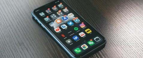 Phone lying on a table showing the home screen with lots of apps with notifications