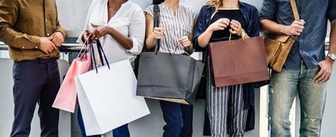 A Line Of People All Standing With Shopping Bags