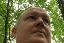 A photo looking up at Greg Knight in a forest
